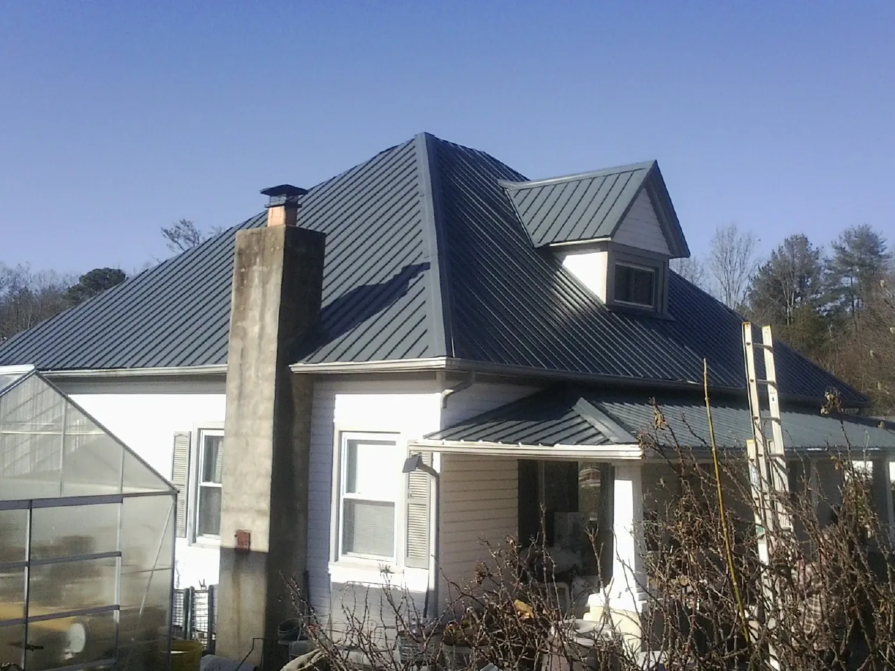 Dark blue standing seam metal roof on a white farmhouse with dormer — Slate & Tile Roof Repair by Roofing Brothers in Salem