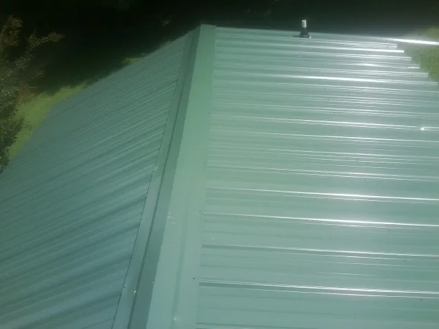 New green metal panels meeting at the ridge of a roof — Flat Roof Repair work by our crew in Salem